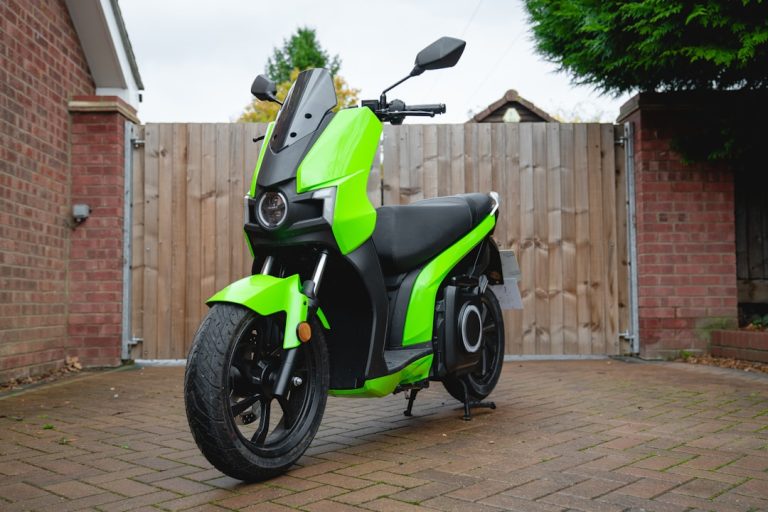 A bright green electric scooter parked in driveway