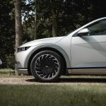 A modern silver car parked on a gravel road.