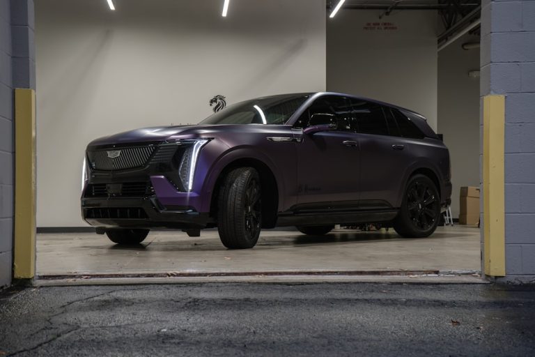 A purple cadillac suv parked in a garage.